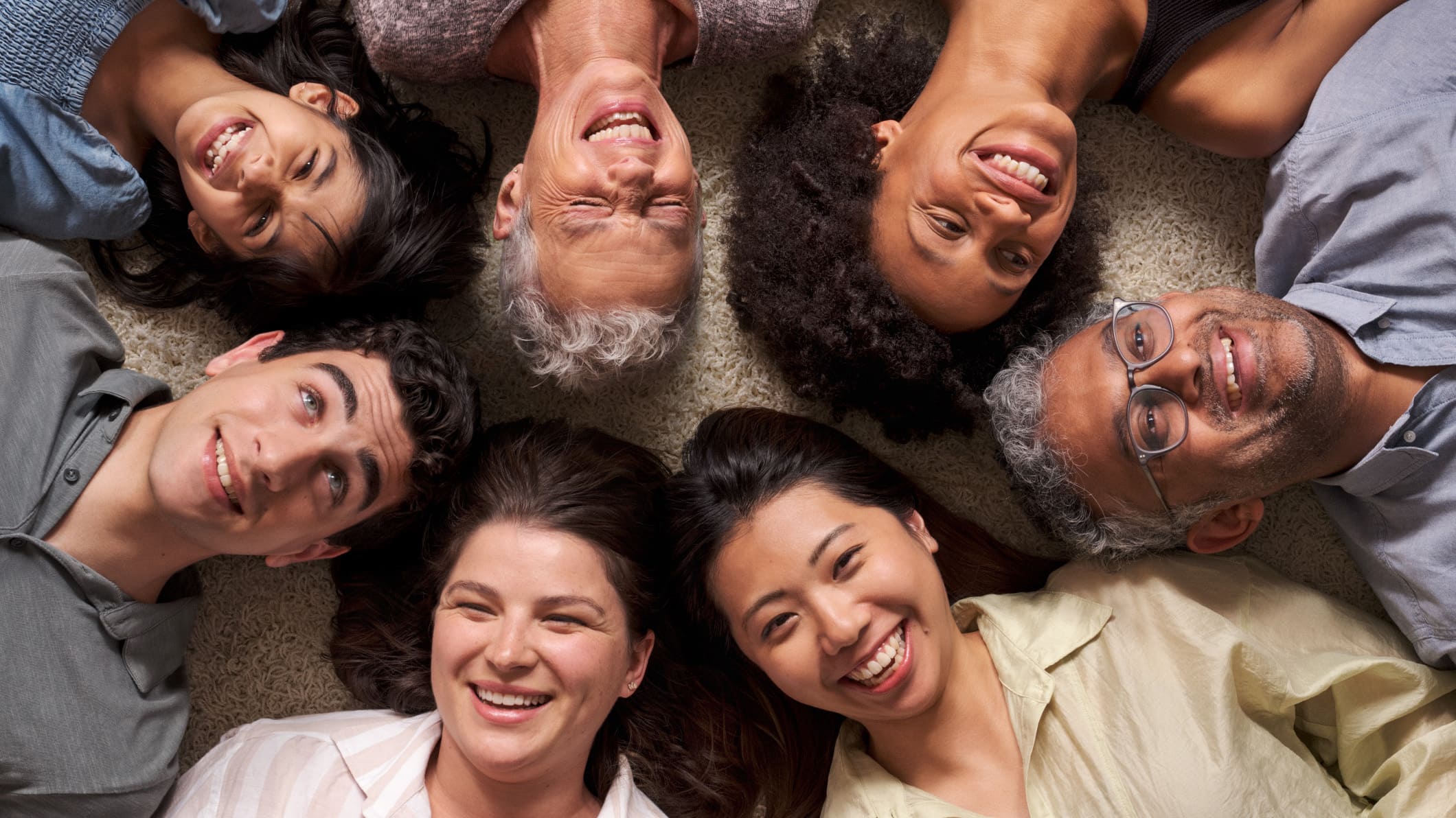 'A diverse group of people gathering with smiles, lying down and looking up.'